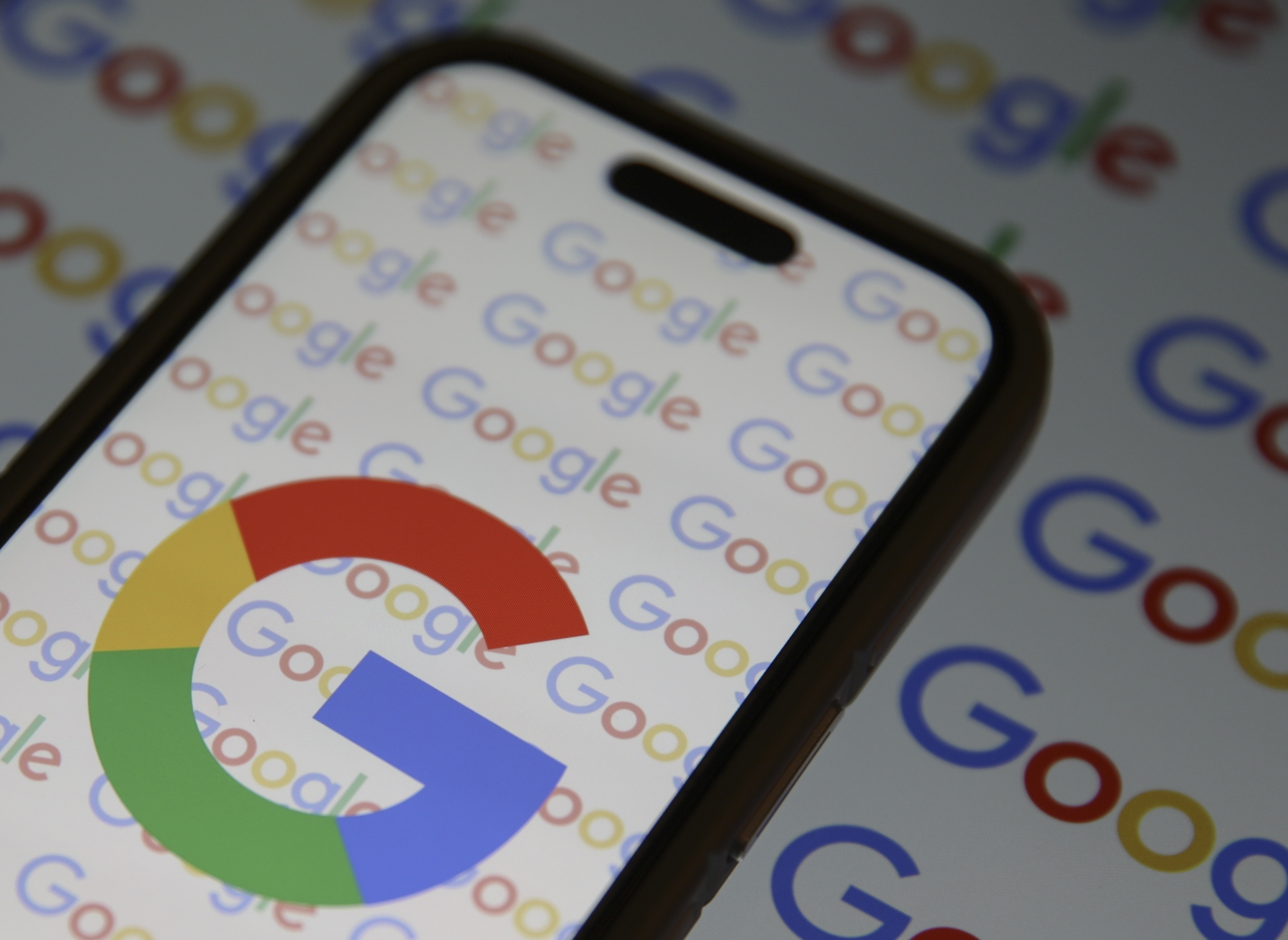 The Google logo prominently displayed on a smartphone and on paperwork beneath it.