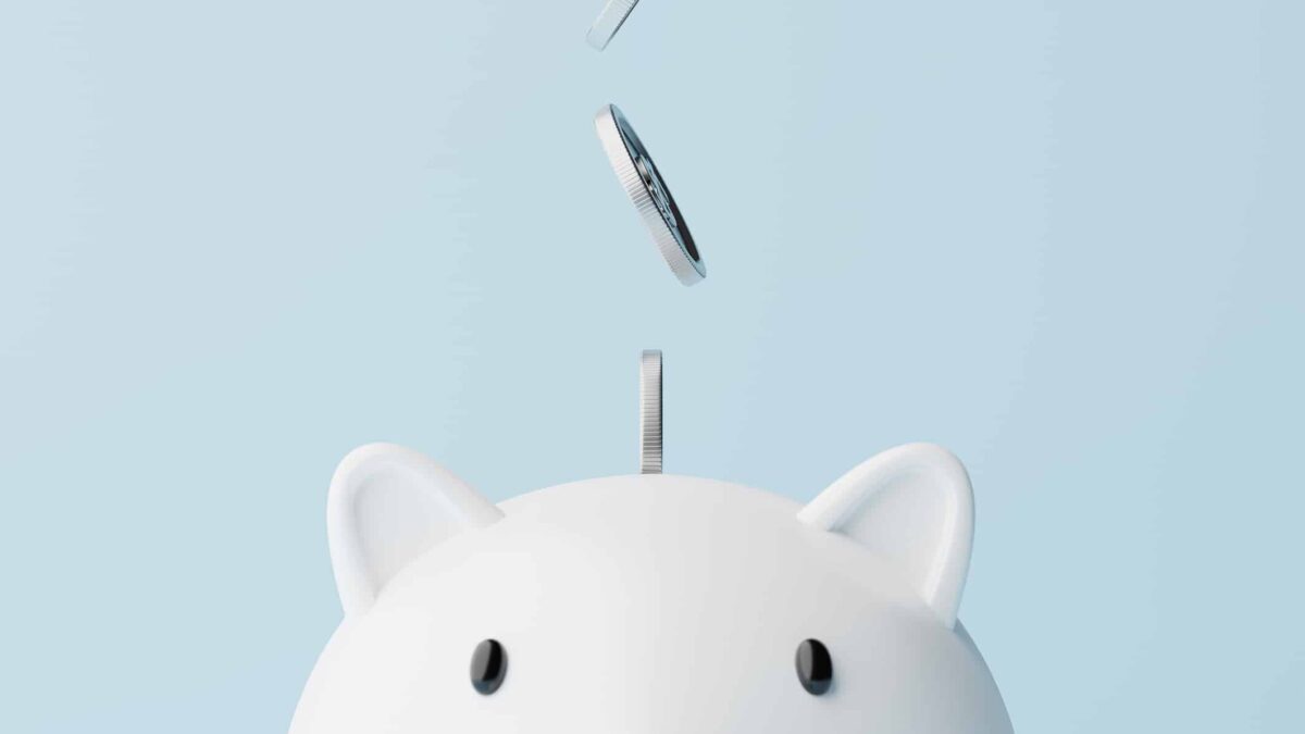 Silver coins fall into a piggy bank.