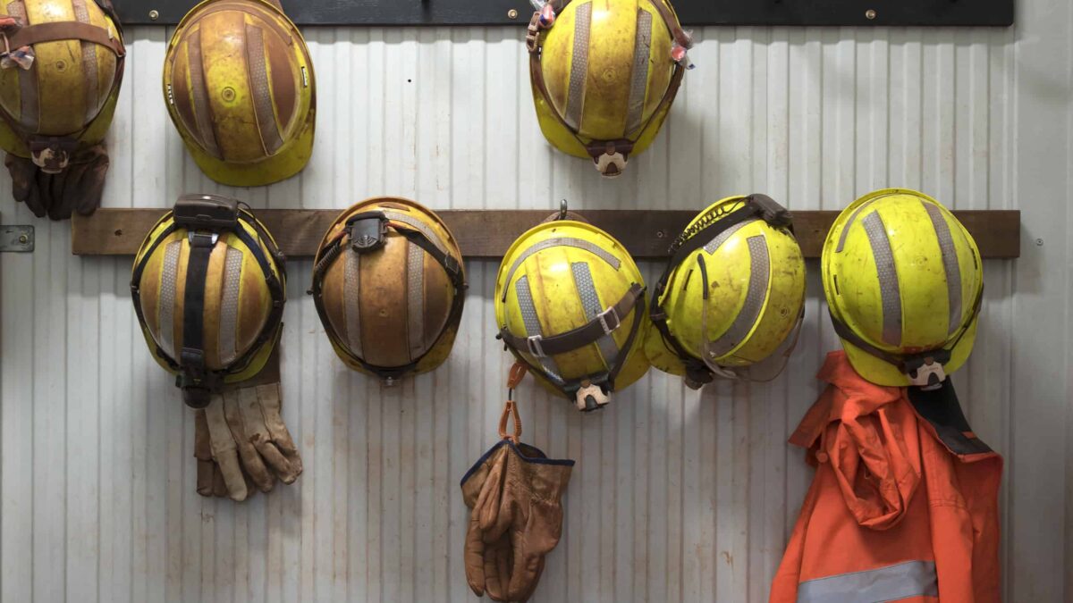 Safety helmets and gloves hang from a rack on a mining site.
