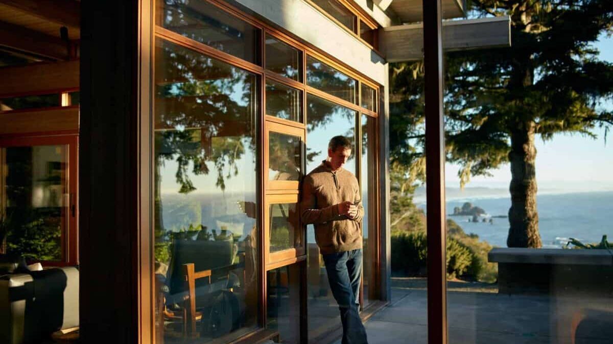 person on phone leaning against outside wall with scenic view at airbnb rental property